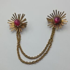 Vintage gold-tone sweater guard with a sunburst design and pink cabochons